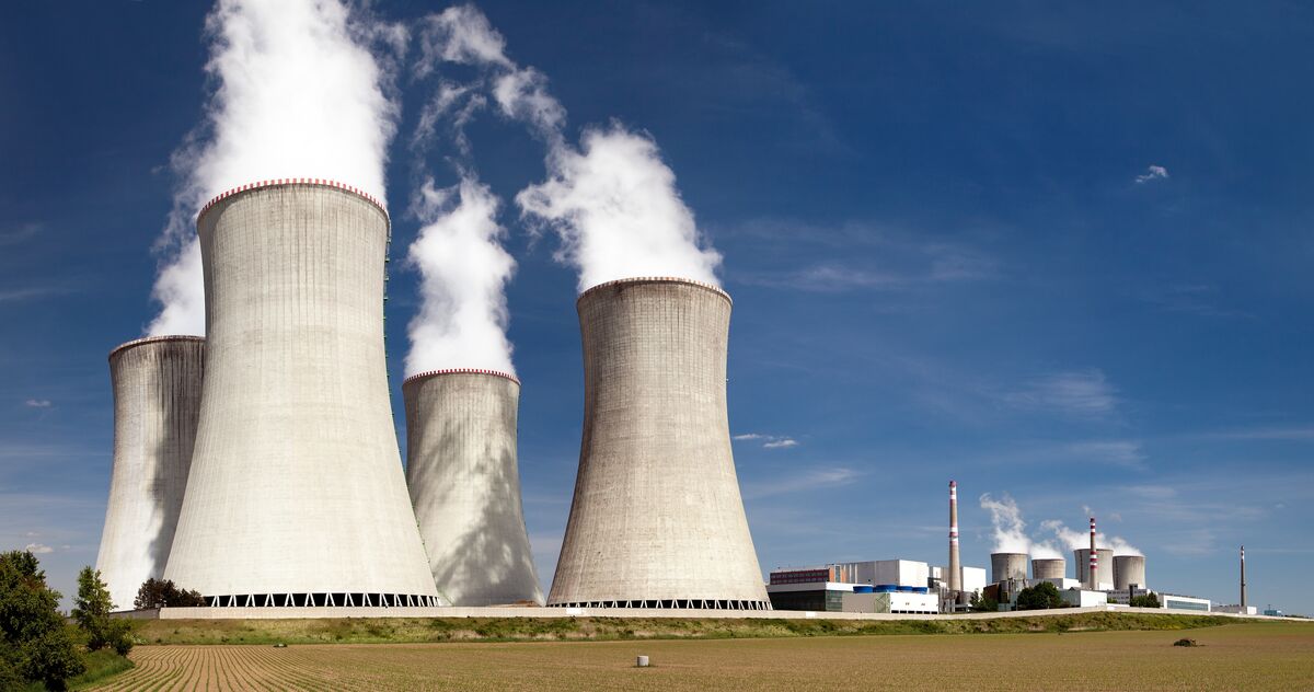 Nuclear power plant with cooling towers releasing steam against a blue sky