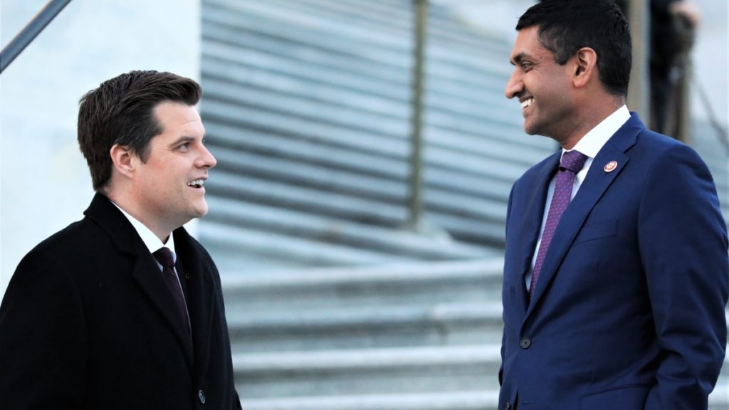 2 men speaking to each other in front of white steps