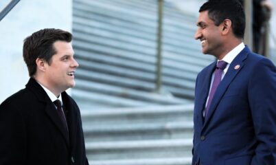 2 men speaking to each other in front of white steps