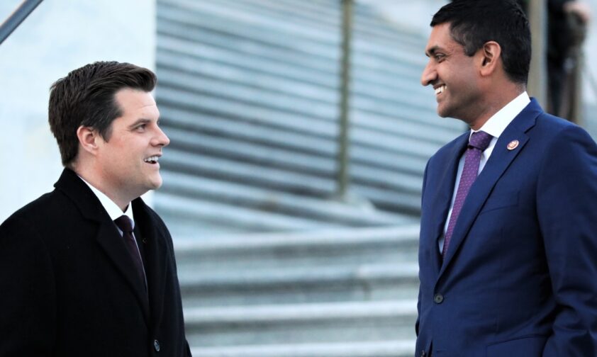 2 men speaking to each other in front of white steps