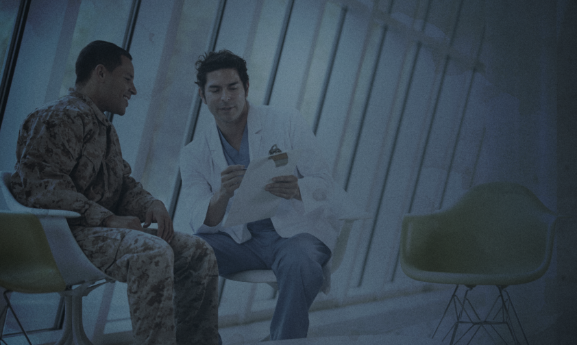 VA Doctor talking to Veteran in Camo in Waiting Room