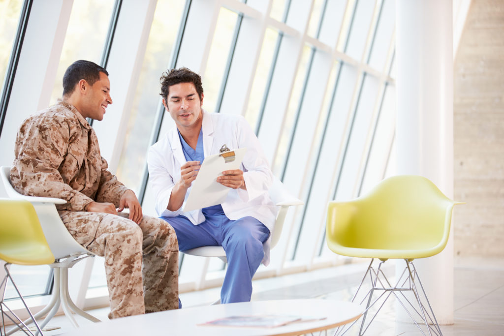 VA Doctor talking to Veteran in Camo in Waiting Room